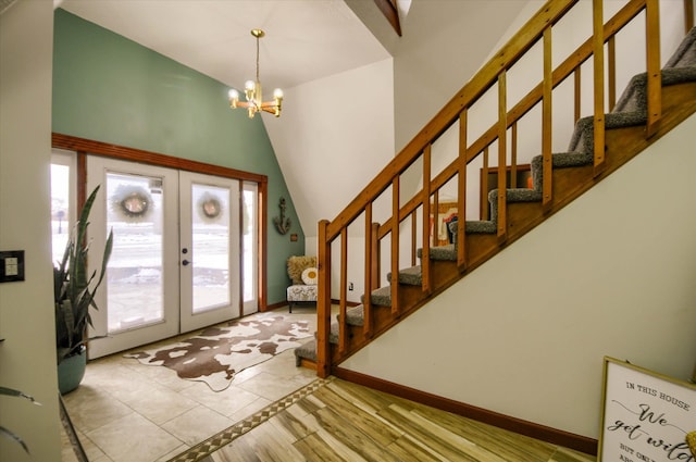 foyer entrance featuring french doors, high vaulted ceiling, a chandelier, and light wood-type flooring