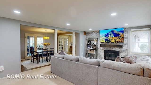 living room featuring ornate columns, french doors, plenty of natural light, and a brick fireplace