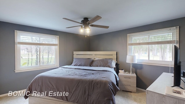 bedroom with ceiling fan, light carpet, and multiple windows