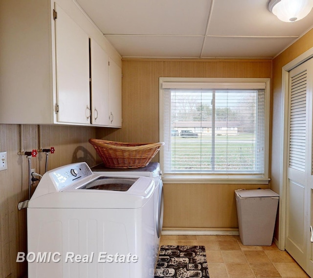 washroom with cabinets, independent washer and dryer, light tile patterned floors, and wooden walls