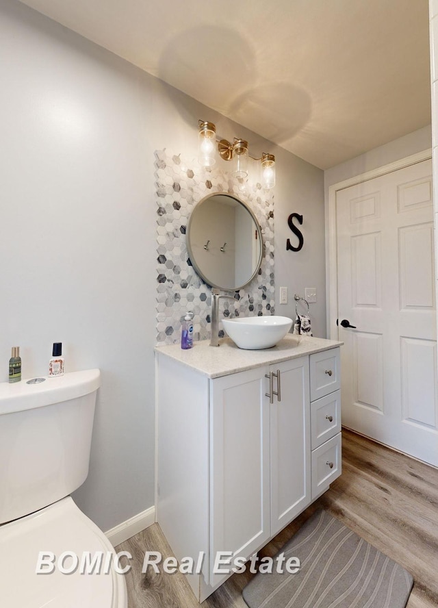 bathroom with wood-type flooring, vanity, and toilet