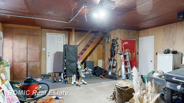 basement featuring wood walls and white fridge