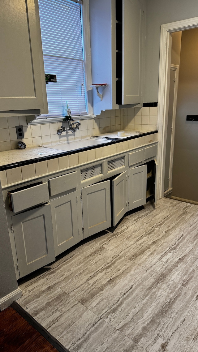 kitchen featuring tile countertops, backsplash, gray cabinets, and light hardwood / wood-style floors