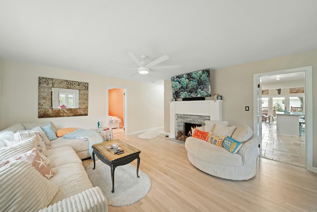 living room featuring a fireplace, ceiling fan, and light hardwood / wood-style flooring