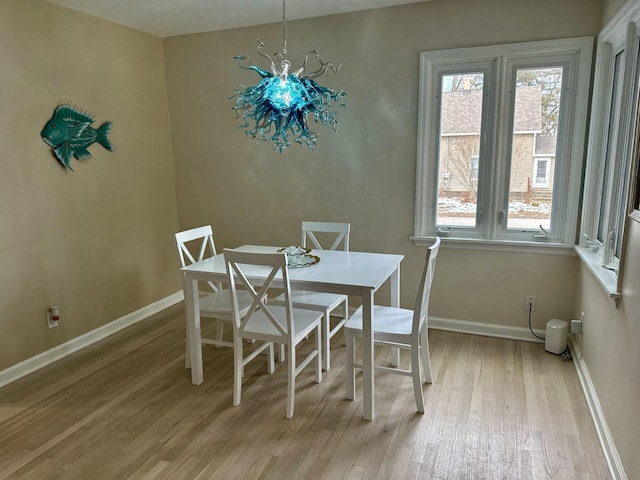 dining space with light hardwood / wood-style floors and a notable chandelier