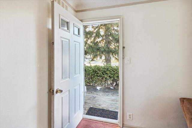 doorway featuring ornamental molding and carpet floors