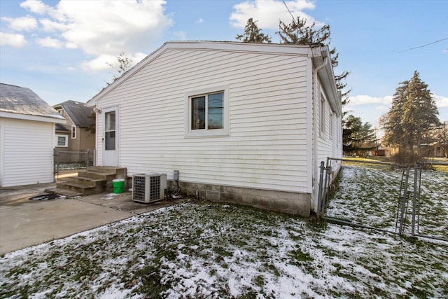 snow covered house with cooling unit and a patio area