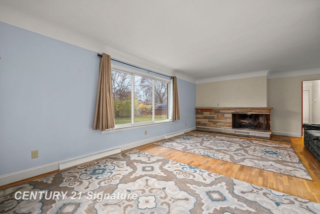 living room with a stone fireplace, wood-type flooring, and a baseboard heating unit