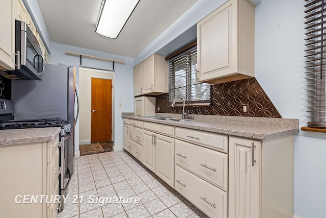 kitchen featuring decorative backsplash, stainless steel appliances, sink, cream cabinetry, and light tile patterned flooring