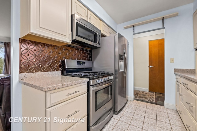 kitchen featuring cream cabinetry, light tile patterned flooring, stainless steel appliances, and tasteful backsplash