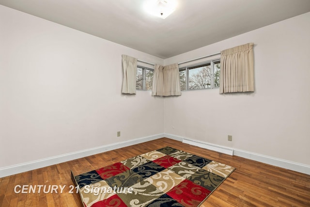 spare room featuring wood-type flooring and baseboard heating