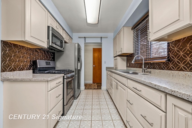 kitchen featuring decorative backsplash, light stone countertops, sink, and appliances with stainless steel finishes