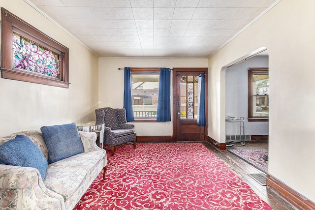 living area featuring ornamental molding, wood finished floors, plenty of natural light, and baseboards