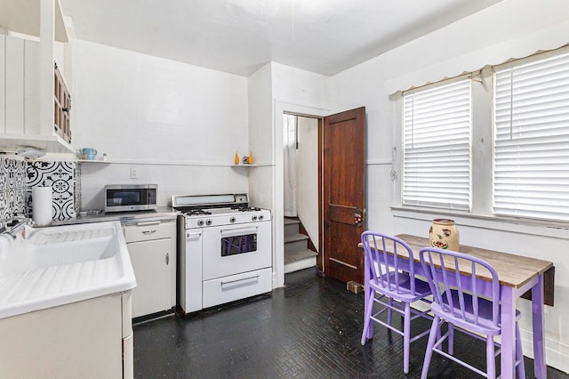 kitchen featuring white range with gas stovetop, stainless steel microwave, white cabinetry, a sink, and dark wood-type flooring