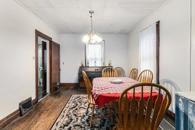 dining room featuring dark wood-style flooring, crown molding, a chandelier, and baseboards