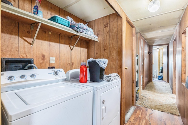 laundry area with hardwood / wood-style floors, washing machine and dryer, and wooden walls