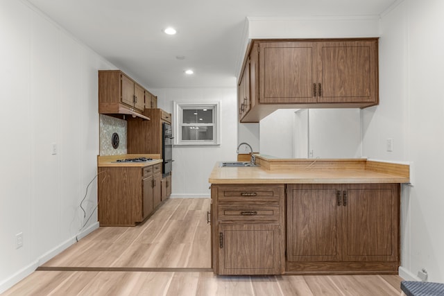 kitchen featuring light hardwood / wood-style floors, white gas stovetop, crown molding, and sink