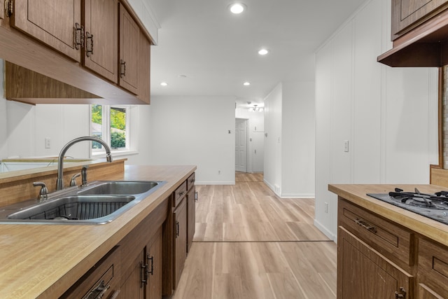 kitchen with light wood-type flooring, black gas cooktop, and sink