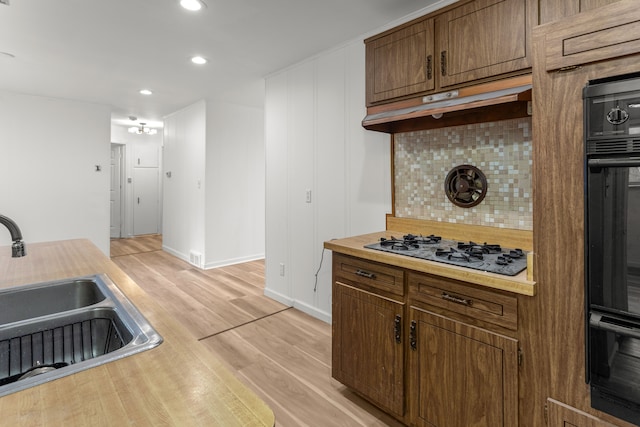 kitchen featuring gas cooktop, light wood-type flooring, oven, and sink