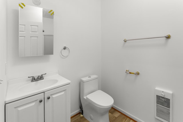 bathroom with hardwood / wood-style floors, vanity, heating unit, and toilet