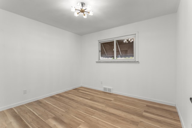 unfurnished room with light hardwood / wood-style flooring and a chandelier