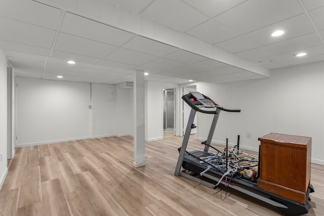 exercise room with a paneled ceiling and light hardwood / wood-style floors