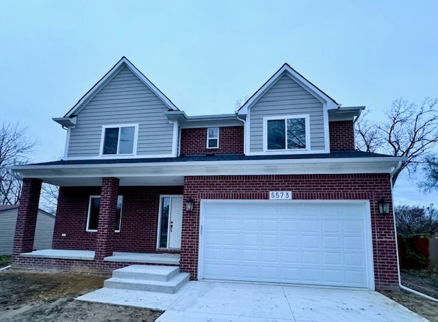 traditional-style home with brick siding, covered porch, driveway, and an attached garage