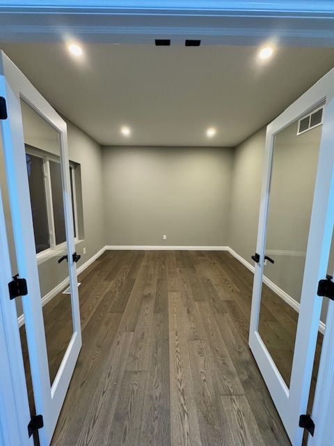 spare room with dark hardwood / wood-style floors and french doors