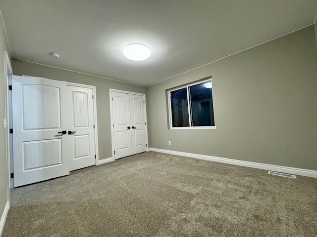 unfurnished bedroom with carpet floors and two closets