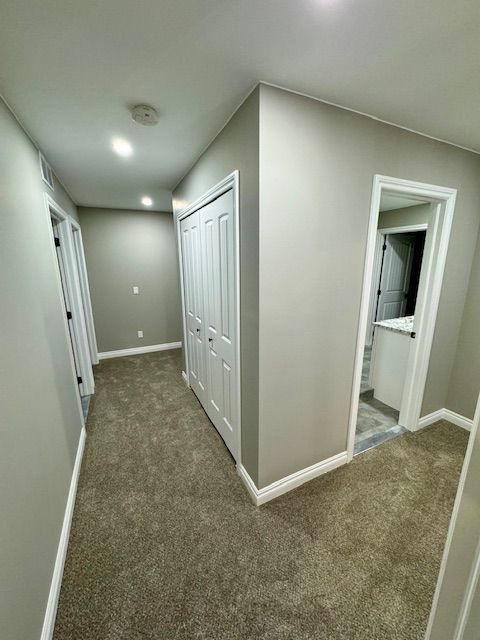 hallway featuring dark colored carpet