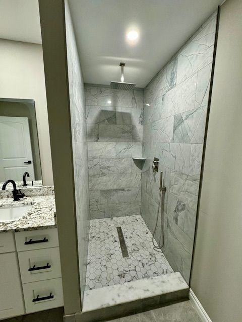 bathroom with a tile shower and vanity