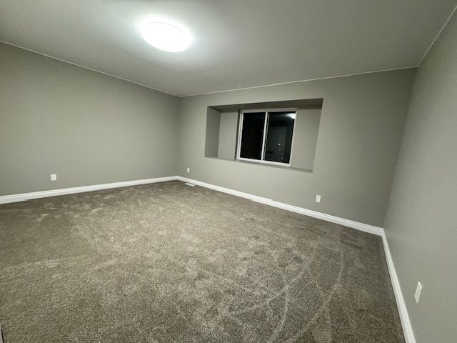 spare room with dark carpet