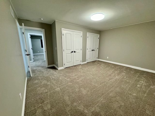 unfurnished bedroom featuring carpet and multiple closets