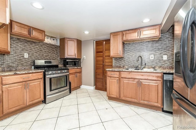 kitchen with sink, stainless steel appliances, light stone counters, backsplash, and light tile patterned floors