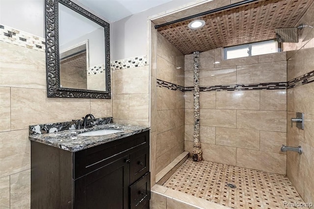 bathroom featuring tiled shower, vanity, and tile walls