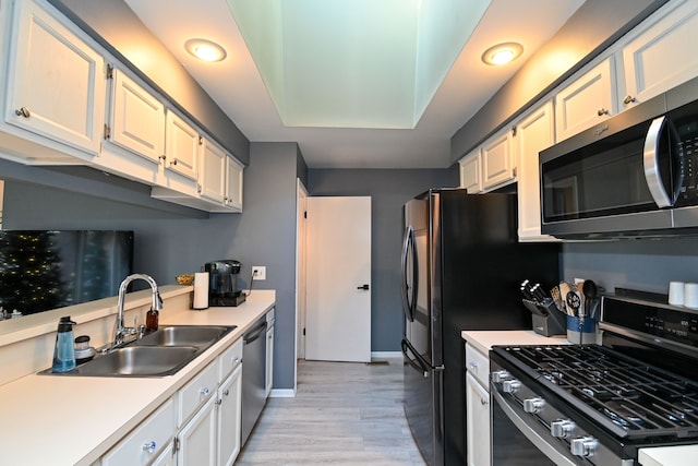 kitchen featuring white cabinets, sink, appliances with stainless steel finishes, and light hardwood / wood-style flooring