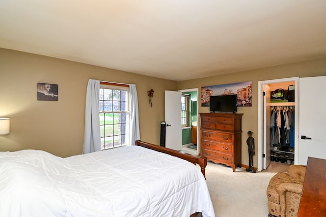 bedroom featuring a walk in closet, light carpet, and a closet