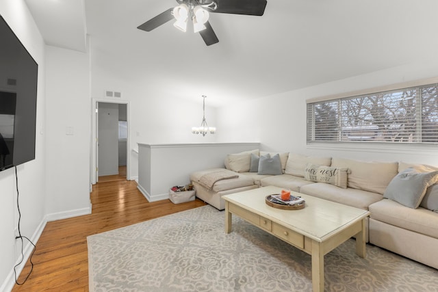 living room with ceiling fan with notable chandelier and hardwood / wood-style flooring