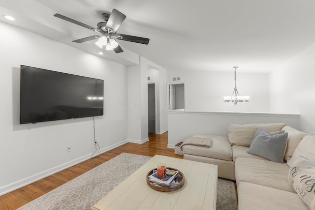 living room featuring ceiling fan with notable chandelier, light wood-type flooring, and lofted ceiling