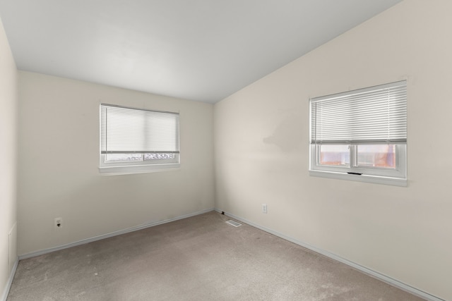 carpeted spare room with vaulted ceiling