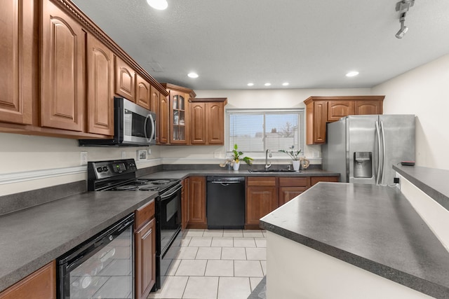 kitchen with a textured ceiling, sink, black appliances, light tile patterned floors, and wine cooler