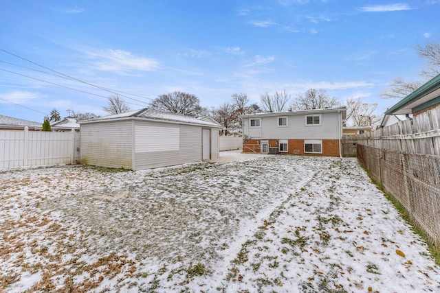 snow covered rear of property featuring an outdoor structure