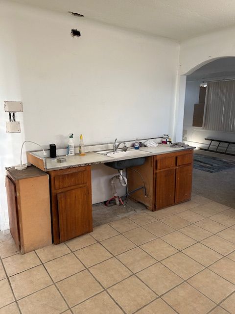 kitchen featuring kitchen peninsula, light tile patterned floors, and sink