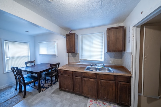 kitchen with tasteful backsplash, dark brown cabinets, sink, and a textured ceiling