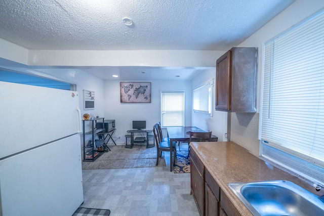 kitchen featuring a textured ceiling, white refrigerator, sink, and carpet