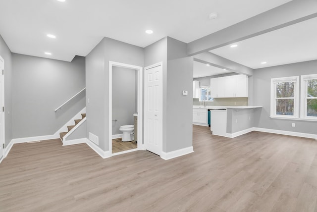 unfurnished living room with a healthy amount of sunlight, sink, and light wood-type flooring