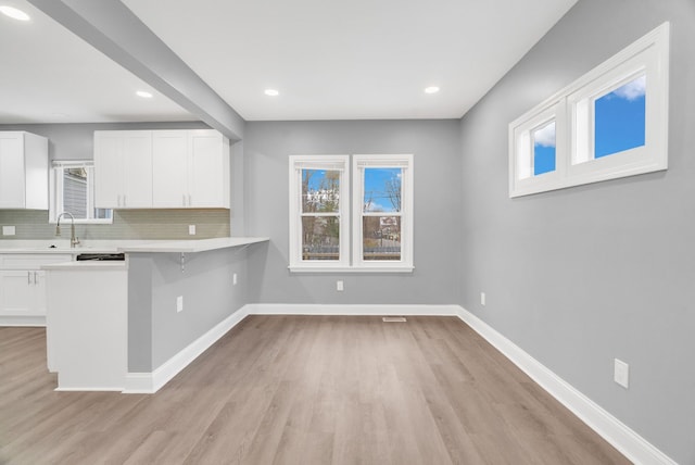 kitchen featuring white cabinetry, tasteful backsplash, a breakfast bar area, and a wealth of natural light