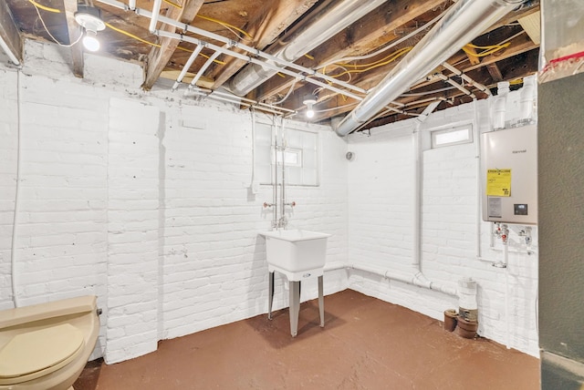 basement with a healthy amount of sunlight, brick wall, and water heater