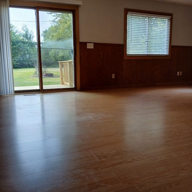 spare room featuring light hardwood / wood-style floors and wood walls