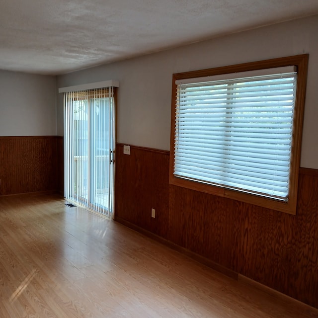 unfurnished room with wood walls and light wood-type flooring